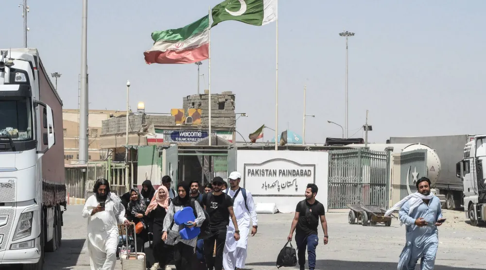 طلاب باكستانيون يعبرون الحدود الباكستانية الإيرانية سيراً على الأقدام بعد عودتهم من إيران في تفتان بإقليم بلوشستان الباكستاني في 19 يونيو 2025  (أ.ف.ب)