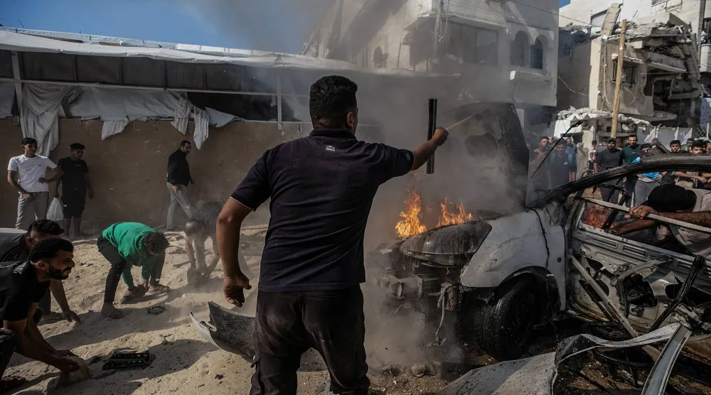 فلسطينيون يحاولون إخماد حريق بمركبة دُمرت جراء غارة جوية إسرائيلية جنوب مدينة غزة يوم الخميس (إ.ب.أ)