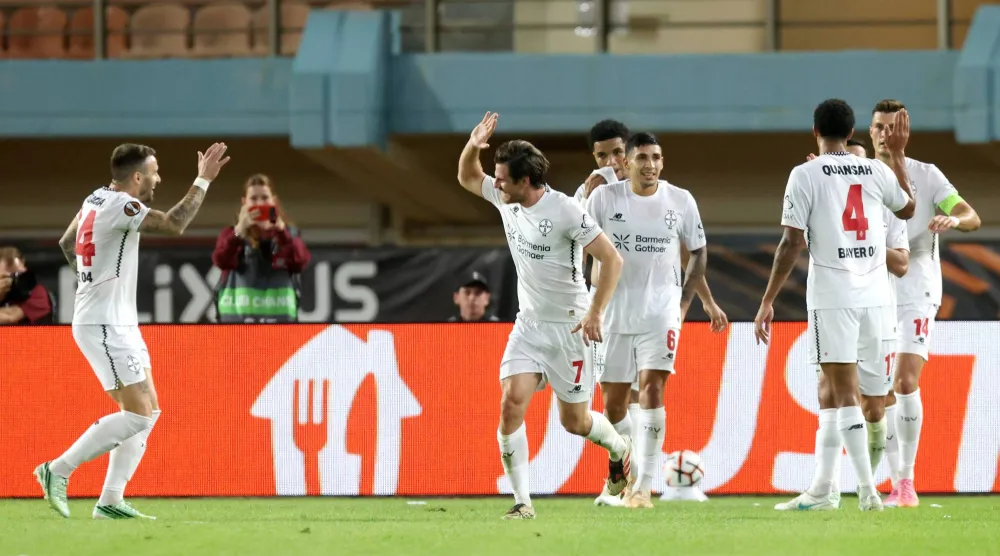 لاعبو باير ليفركوزن الألماني يحتفلون بتسجيل هدف أمام أوفي كريت اليوناني خلال مواجهة الفريقين (أ.ب)