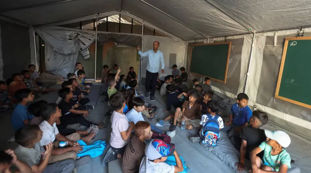 Gazze Şeridi’nin güneyindeki Han Yunus’ta, çadırda kurulan bir sınıfta yeni akademik yılın ilk gününe katılan Filistinli öğrenciler, 19 Eylül 2026 (Reuters)