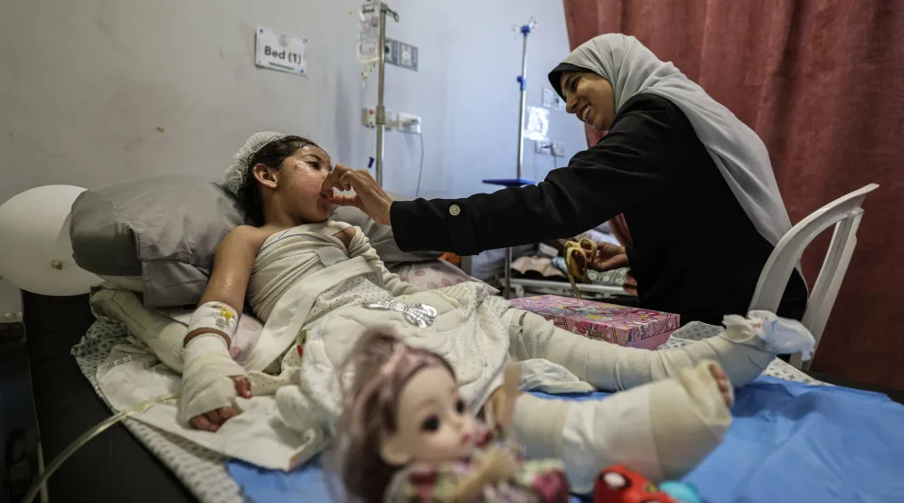 فلسطينية تهتم بطفلة تتلقى العلاج من حروق أصابتها إثر هجوم إسرائيلي على مبنى سكني قتل والديها بمدينة غزة في 15 أكتبر 2026 (د.ب.أ)