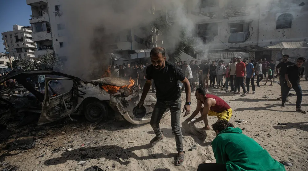 فلسطينيون يحاولون إخماد حريق في مركبة دُمِّرت جرَّاء غارة جوية إسرائيلية جنوب مدينة غزة (إ.ب.أ)
