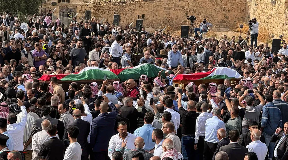 مشيعون يحملون جثامين ضحايا الهجوم الذي وقع قبل يومين في كنيسة للروم الأرثوذكس وذلك خلال مراسم جنازتهم في قرية حمود بمحافظة الكرك في الأردن (أ.ف.ب)