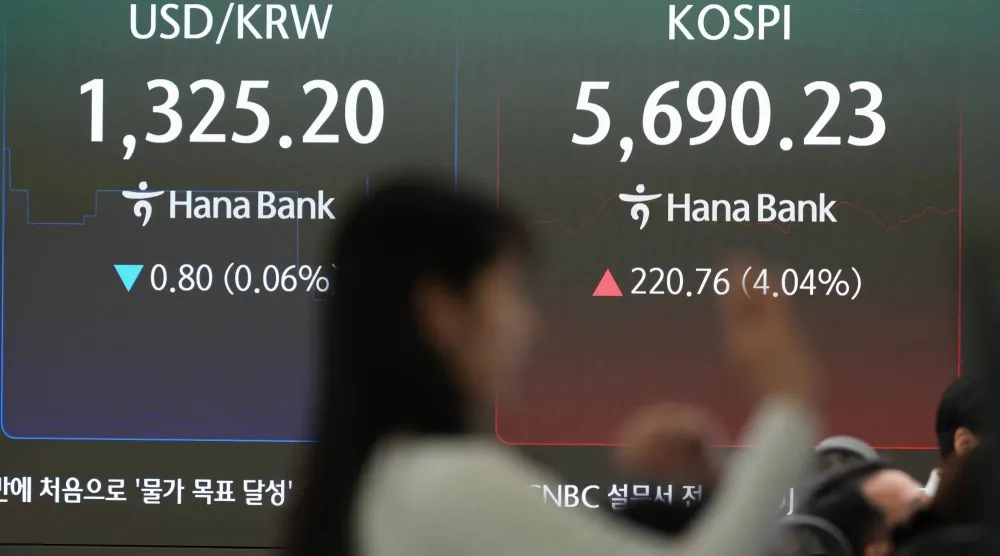 متداولة تقف بالقرب من شاشات تعرض مؤشر «كوسبي» وسعر صرف العملات بين الدولار والوون الكوري الجنوبي في غرفة تداول تابعة لبنك هانا في سيول (أ.ب)