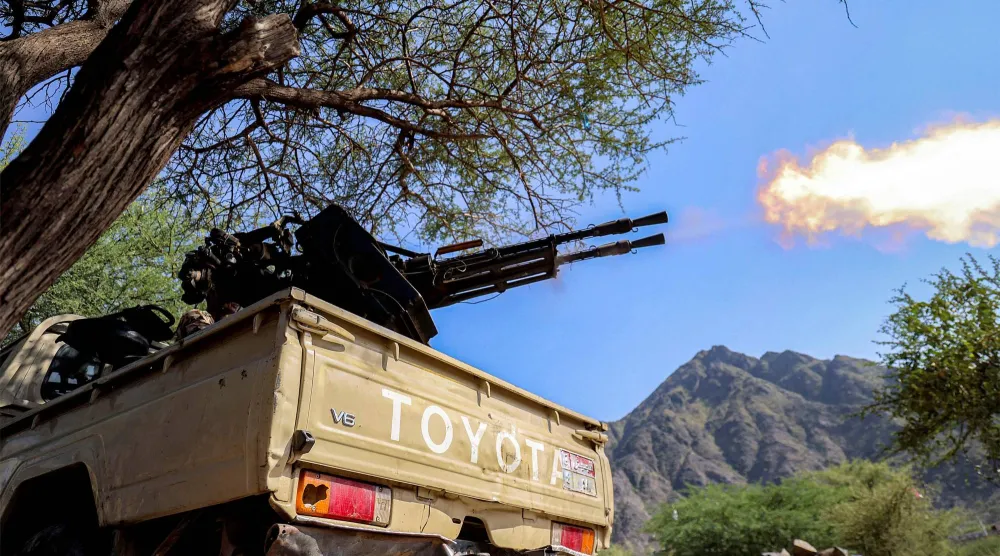 A fighter loyal to Yemen's internationally-recognized government fires a turret from the back of a pickup truck at a position along the frontlines against the Houthis around Mount al-Midan in Yemen's western Taiz province on October 26, 2026.  (Photo by Ahmad AL-BASHA / AFP) / 