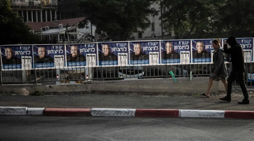 Kudüs’te bir oy kullanma merkezinin önünde, Gadi Eisenkot liderliğindeki Yashar Partisi’nin seçim afişlerinin önünden geçen insanlar. (AFP)