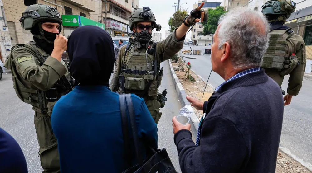 فلسطينيون يتجادلون مع جنود من الجيش الإسرائيلي خلال احتجاج ضد تهجيرهم من منازلهم في مدينة الخليل بالضفة الغربية (رويترز)