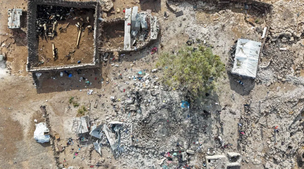 لقطة جوية لأشخاص يتفقدون الأضرار في موقع استهدفته غارات جوية أردنية الليلة الماضية على قرية في منطقة اللجاة الواقعة في الريف الشمالي الشرقي لدرعا بسوريا (أ.ف.ب)