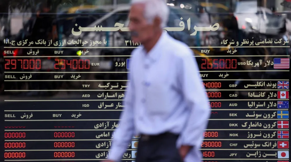 إيراني يسير أمام لوحة تعرض أسعار صرف العملات في طهران يوم 27 أكتوبر 2026 (رويترز)
