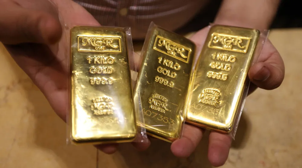 بائع يعرض سبائك ذهبية في متجر مجوهرات داخل سوق الذهب في السوق القديمة بدبي (إ.ب.أ)