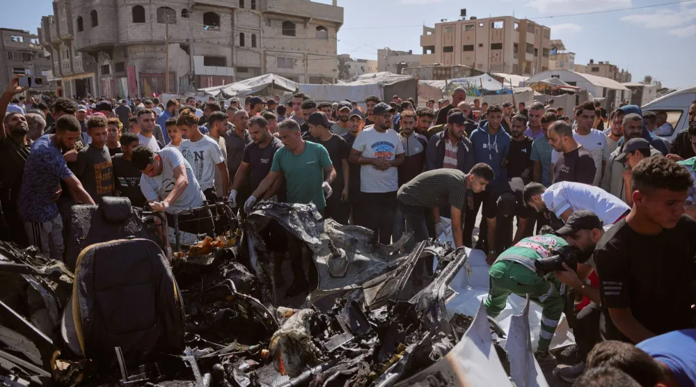 فلسطينيون يتفقدون حطام مركبة دُمرت في غارة جوية إسرائيلية بمخيم المغازي للاجئين وسط قطاع غزة 29 أكتوبر 2026 (أ.ب)