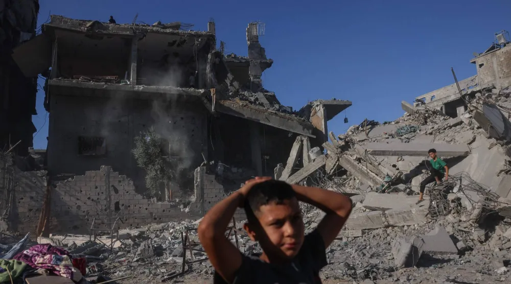 صبيان فلسطينيان وسط الدمار بعد استهداف مبنى بغارة إسرائيلية غرب جباليا شمال قطاع غزة الجمعة (أ.ف.ب)