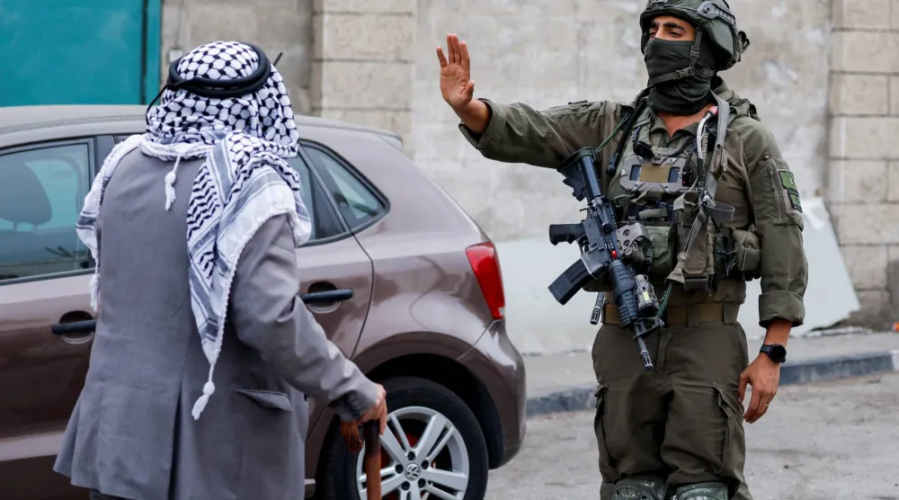 جندي إسرائيلي يشير بيده نحو رجل فلسطيني خلال احتجاج نظمه سكان فلسطينيون ضد تهجيرهم من أحد الأحياء وفي مدينة الخليل بالضفة الغربية قي 27 أكتوبر 2026 (رويترز)