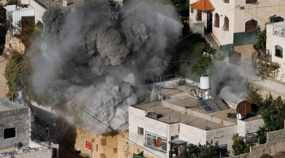 سحابة من الغبار تتصاعد بينما يهدم الجيش الإسرائيلي منزل فلسطيني في مدينة الخليل بالضفة الغربية (رويترز)