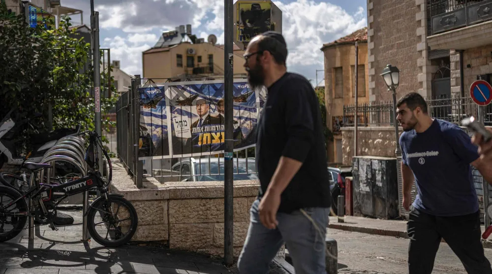 إسرائيليون يسيرون أمام ملصق لرئيس الوزراء الإسرائيلي بنيامين نتنياهو في القدس (أ.ف.ب)