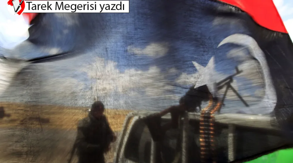 Ecdebiye şehrinin batı kapısında, cephe hattına yakın bir yerde, Libya Krallığı bayrağının arkasında muhalif güçlerden bir savaşçı(Reuters)