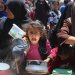 طفلة فلسطينية تصطفّ مع نساء آخريات للحصول على الطعام من تكية خيرية في مخيم النصيرات بقطاع غزة (أ.ف.ب)