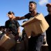 شخص يلوّح بيده وهو يحمل صندوقاً بينما يتجمع الفلسطينيون بالقرب من موقع توزيع المساعدات الذي تديره مؤسسة مدعومة من الولايات المتحدة في رفح (رويترز)