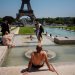 سياح يستريحون في نافورة أمام برج إيفل في باريس في 1 يوليو 2025 مع ارتفاع درجات الحرارة في فرنسا (أ.ف.ب)