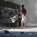 أم فلسطينية وابنتها تهرعان للاحتماء خلال غارة إسرائيلية على مخيم البريج في وسط قطاع غزة يوم 4 يوليو 2025 (أ.ف.ب)