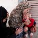 فلسطينية تهدّئ من روع طفل مع نقل ضحايا هجوم إسرائيلي إلى مستشفى في دير البلح يوم الخميس (رويترز)