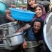 فلسطينيون يصرخون أثناء طلب الطعام من مطبخ خيري وسط أزمة الجوع في غزة (رويترز)