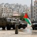 فلسطيني يلوّح بعَلم بلاده أمام آليات عسكرية إسرائيلية في طولكرم (رويترز)
