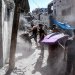 أشخاص يتفقدون أنقاض مبنى مدمَّر إثر قصف إسرائيلي على مخيم البريج للاجئين الفلسطينيين وسط قطاع غزة (أ.ف.ب)