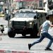  شاب فلسطيني يركض أمام عربة عسكرية عقب اقتحام الجيش الإسرائيلي مدينة نابلس أمس (أ.ب)