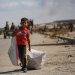 طفل فلسطيني يحمل حقيبة ويجرّ أخرى خلفه بالقرب من معبر نتساريم وسط قطاع غزة (أ.ف.ب)