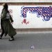 إيرانية تسير بجانب لوحة جدارية مناهضة للولايات المتحدة على جدار السفارة الأميركية السابقة في طهران أغسطس 2023 (أرشيفية - أ.ب)