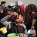طفل فلسطيني نازح يأكل بعد حصوله على طعام يوم الأحد في ملجأ تقيم فيه عائلات بالنصيرات وسط قطاع غزة (أ.ف.ب)