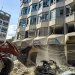 جرافة تزيل الأنقاض والركام من أمام مبنى متضرر عقب قصف إسرائيلي ليليّ على مدينة صور جنوب لبنان (أ.ف.ب)