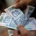 موظف يعد أوراق الروبية الهندية داخل مكتب صرافة خاص في نيودلهي (رويترز)