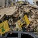 نازحون عائدون إلى ضاحية بيروت الجنوبية يحملون علم «حزب الله» وصورة أمين عام الحزب نعيم قاسم (أ.ب)