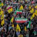 إيرانيون يحملون أعلام إيران و«حزب الله» في مسيرة في طهران (أ.ب)