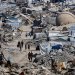 فلسطينيون يسيرون وسط مبانٍ دمَّرها القصف الإسرائيلي خلال الحرب في مخيم جباليا للاجئين شمال قطاع غزة يوم الجمعة (رويترز)