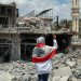 لبنانية تضع العَلَم اللبناني على كتفيها وتتفقد الدمار في ساحة مدينة النبطية بجنوب لبنان (إ.ب.أ)