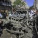 فلسطينيون يتفقدون سيارة استهدفتها طائرات إسرائيلية مسيّرة في حي الرمال في غزة (د.ب.أ)