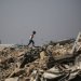 صبي فلسطيني يشق طريقه وسط الأنقاض قرب مخيم للنازحين في منطقة النصيرات وسط غزة يوم الأحد (أ.ف.ب)