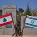 جنديان إسرائيليان عند نصب  على الحدود الشمالية  مرفوع أمامه علما لبنان وإسرائيل (أ.ب)