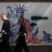 إيرانيتان تمران أمام جدارية مناهضة للولايات المتحدة على حائط سفارتها السابقة في طهران (رويترز)