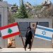 يهودان من طائفة «الحريديم» (المتشددين دينياً) يقفان بجوار العلمين الإسرائيلي واللبناني في موقع عند الحدود مع لبنان في شمال إسرائيل (أ.ف.ب)