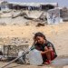فتاة فلسطينية تملأ أوعيةً بالماء المستخرج من بقايا أنابيب تحت الأرض بمخيم للنازحين جراء الحرب في حي الشيخ رضوان بمدينة غزة (أ.ف.ب)