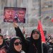يرفع أحد المشيعين لافتة تحمل صورتي الرئيس ترمب ورئيس الوزراء الإسرائيلي بنيامين نتنياهو مع عبارة «الانتقام حتمي» (أ.ف.ب)