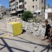 فتيان فلسطينيون ينظرون إلى كتلة خرسانية صفراء تُشير إلى «المنطقة الصفراء» الخاضعة للسيطرة العسكرية الإسرائيلية في حي طفاح بمدينة غزة (رويترز)