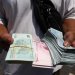 تاجر عملات يحمل ريالاً إيرانياً في السوق الكبيرة بطهران (رويترز)