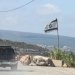 مدنيون من القرى المسيحية في جنوب لبنان يعبرون الطريق الساحلي جنوباً ضمن قافلة ويبدو العلم الإسرائيلي على مدخل بلدة الناقورة في يوليو 2026 (أرشيفية - أ.ف.ب)