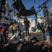 فلسطينيون يعاينون الأضرار بعد غارة إسرائيلية في مدينة غزة الجمعة (إ.ب.أ)