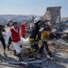 عناصر الدفاع المدني ورجل إطفاء ينتشلون جثة من موقع انفجار مستودع للتخزين المؤقت للأسلحة بالقرب من سرمدا بمحافظة إدلب الأربعاء (أ.ب)